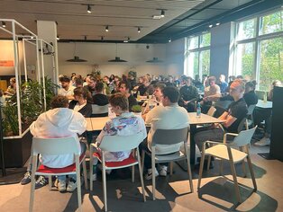Abbildung von mehreren Menschen im Speisesaal.