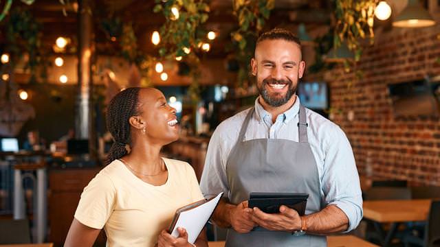 Abbildung von zwei Personen in einem Restaurant mit Notizblock und Tablet.