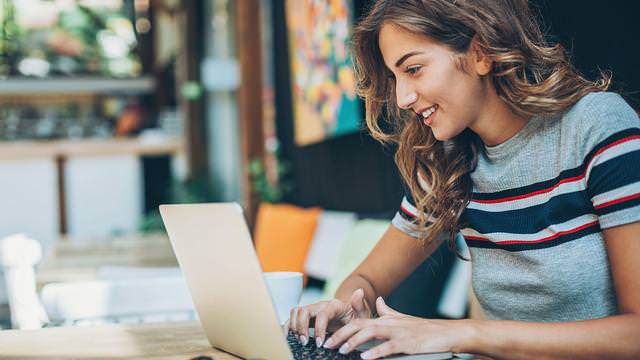 Abbildung einer Frau mit Laptop an einem Tisch.