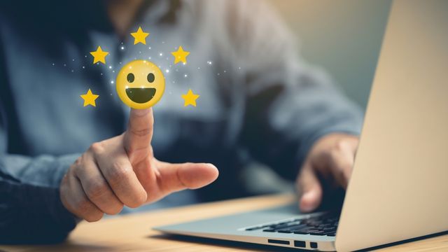 Abbildung einer Person mit Laptop, auf dem ausgestreckten Finger schwebt ein Smiley mit fünf Sternen.