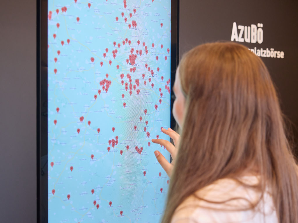 Abbildung einer Person an einem großen Touchscreen mit einer Karte.